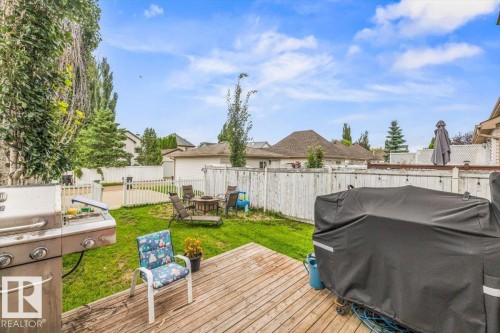 Expansive backyard featuring a wood deck, green lawn, and privacy fencing - 4744 Terwillegar Common Nw, Edmonton, AB - Outdoor With Deck Patio Veranda