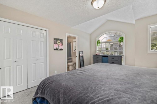 Vaulted ceiling with an arched window, white paneled bifold closet doors, and recessed lighting - 4744 Terwillegar Common Nw, Edmonton, AB - Indoor Photo Showing Bedroom