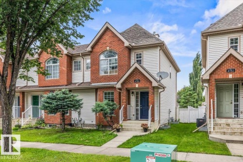 Brick facade with arched windows, white siding, gabled rooflines, and a paved walkway - 4744 Terwillegar Common Nw, Edmonton, AB - Outdoor With Facade