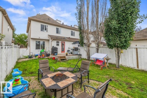 Fenced backyard featuring a wood-decked patio and mature trees - 4744 Terwillegar Common Nw, Edmonton, AB - Outdoor With Deck Patio Veranda With Exterior