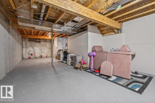 Unfinished basement with exposed ceiling joists and support beams, concrete flooring, and a portion of finished wall - 4744 Terwillegar Common Nw, Edmonton, AB - Indoor Photo Showing Basement