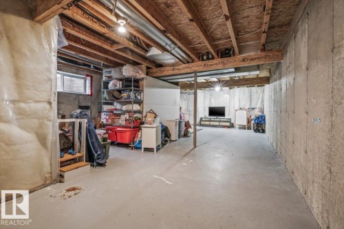 Unfinished lower level with exposed ceiling joists, concrete foundation walls, and a small egress window - 4744 Terwillegar Common Nw, Edmonton, AB - Indoor Photo Showing Basement