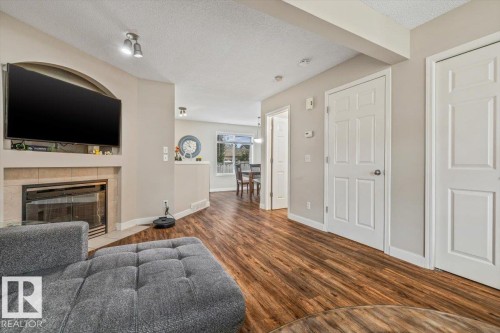 Wood-finish flooring, built-in fireplace with tile surround, recessed lighting, and panel interior doors - 4744 Terwillegar Common Nw, Edmonton, AB - Indoor Photo Showing Living Room With Fireplace