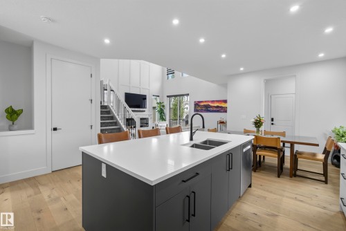 Kitchen island with a white countertop and dark cabinetry, featuring a dual sink and a black gooseneck faucet - 7314 Morgan Road Nw, Edmonton, AB - Indoor Photo Showing Kitchen With Double Sink