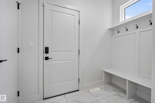 White painted doors with matte black hardware, built-in bench with storage, integrated wall hooks, and large format tile flooring - 7314 Morgan Road Nw, Edmonton, AB - Indoor Photo Showing Other Room