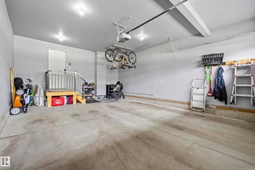 Spacious garage featuring a concrete floor, built-in wooden steps with metal railing, and overhead lighting - 7314 Morgan Road Nw, Edmonton, AB - Indoor Photo Showing Garage