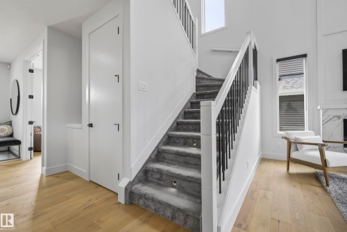 Hardwood-finish flooring, carpeted staircase with inset lighting, black metal balusters, and a contemporary window with blinds - 7314 Morgan Road Nw, Edmonton, AB - Indoor Photo Showing Other Room