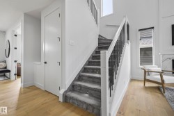 Hardwood-finish flooring, carpeted staircase with inset lighting, black metal balusters, and a contemporary window with blinds - 