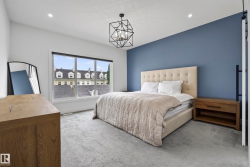Recessed lighting, geometric chandelier, large window, accent wall, and light-colored carpeting - 7314 Morgan Road Nw, Edmonton, AB - Indoor Photo Showing Bedroom