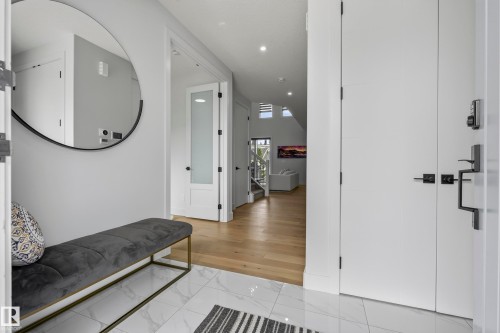 Entryway featuring white marble-look tile flooring and a round wall-mounted mirror - 7314 Morgan Road Nw, Edmonton, AB - Indoor Photo Showing Other Room