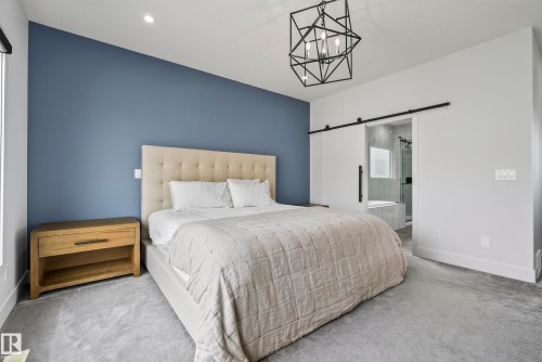 Recessed lighting, geometric chandelier, tufted headboard, barn door, and gray carpeting - 7314 Morgan Road Nw, Edmonton, AB - Indoor Photo Showing Bedroom