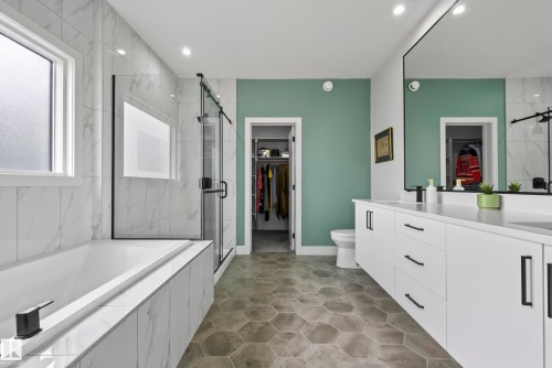 Hexagonal floor tiling, dual vanity with solid surface countertops, built-in soaking tub, glass-enclosed shower, and recessed lighting - 7314 Morgan Road Nw, Edmonton, AB - Indoor Photo Showing Bathroom
