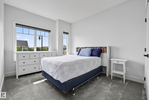 Bright room featuring two windows with dark roller blinds, light gray wall paint, and gray carpeting - 7314 Morgan Road Nw, Edmonton, AB - Indoor Photo Showing Bedroom