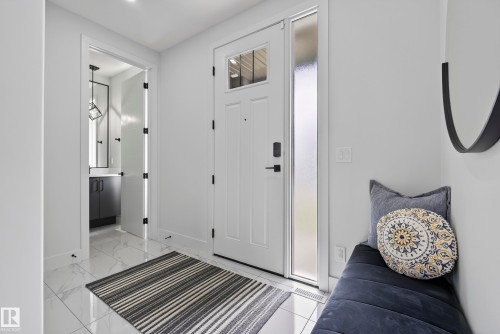 White paneled door with glass insert, frosted sidelight, and marble-look tile flooring - 7314 Morgan Road Nw, Edmonton, AB - Indoor Photo Showing Other Room