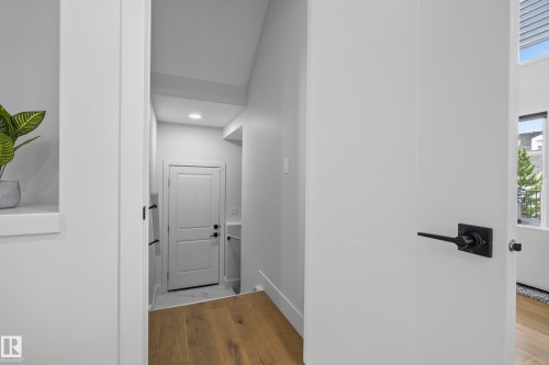 Wood-finish flooring, recessed lighting, and a white paneled door with black hardware - 7314 Morgan Road Nw, Edmonton, AB - Indoor Photo Showing Other Room