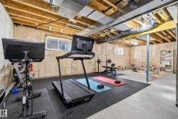 Unfinished basement with exposed ceiling joists and ductwork, concrete flooring, and insulated walls - 