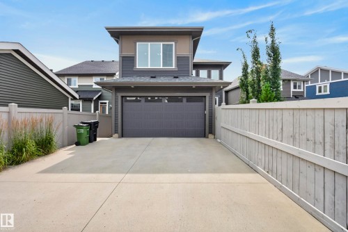 Contemporary exterior with a flat roofline, attached garage, large driveway, and light-toned fencing - 7314 Morgan Road Nw, Edmonton, AB - Outdoor
