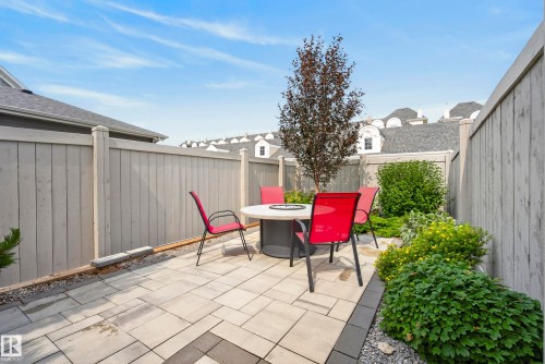 Paved patio area featuring interlocking pavers, a privacy fence, and integrated garden beds with various plantings - 7314 Morgan Road Nw, Edmonton, AB - Outdoor