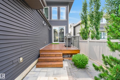 Wood-finish deck with railing, leading to a paver patio and landscape rock beds - 7314 Morgan Road Nw, Edmonton, AB - Outdoor With Exterior