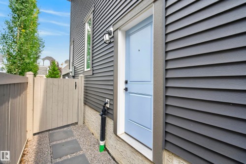 Dark gray horizontal siding exterior with a light blue entry door, featuring a black exterior light fixture - 7314 Morgan Road Nw, Edmonton, AB - Outdoor