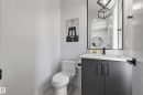 Powder room featuring a sleek vanity with a built-in sink, dark cabinetry, a framed mirror, and a modern toilet - 7314 Morgan Road Nw, Edmonton, AB  - Indoor Photo Showing Bathroom 