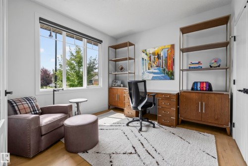 Wood-finish flooring, white walls, large multi-pane window, and built-in shelving units with lower cabinetry - 7314 Morgan Road Nw, Edmonton, AB - Indoor