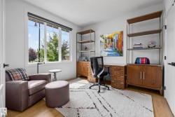 Wood-finish flooring, white walls, large multi-pane window, and built-in shelving units with lower cabinetry - 