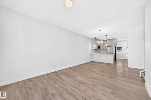 Wood-finish flooring throughout, with a recessed ceiling light - 3816 Chrustawka Place Sw, Edmonton, AB - Indoor Photo Showing Kitchen