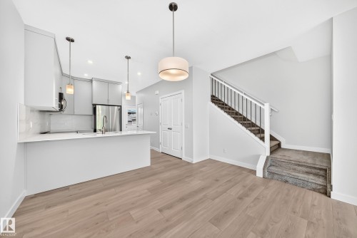 Modern kitchen featuring light gray cabinetry, stainless steel appliances, and a white countertop with integrated sink - 3816 Chrustawka Place Sw, Edmonton, AB - Indoor Photo Showing Other Room