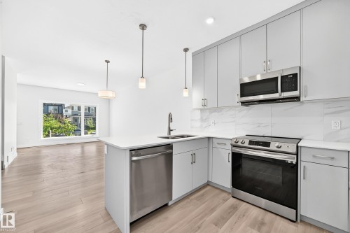 Kitchen featuring light gray cabinetry, stainless steel appliances, white countertops, and a white tile backsplash - 3816 Chrustawka Place Sw, Edmonton, AB - Indoor Photo Showing Kitchen With Double Sink With Upgraded Kitchen