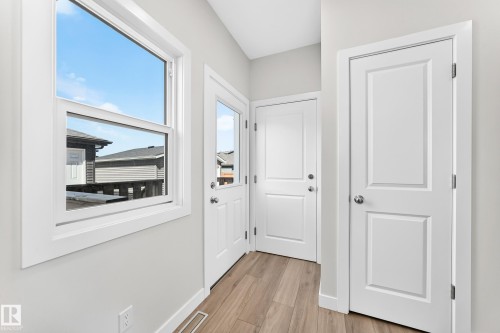 White paneled doors, large window, and wood-finish flooring - 3816 Chrustawka Place Sw, Edmonton, AB - Indoor Photo Showing Other Room