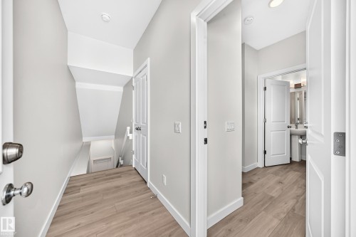 Wood-finish flooring throughout, white paneled doors, and recessed ceiling lighting - 3816 Chrustawka Place Sw, Edmonton, AB - Indoor Photo Showing Other Room