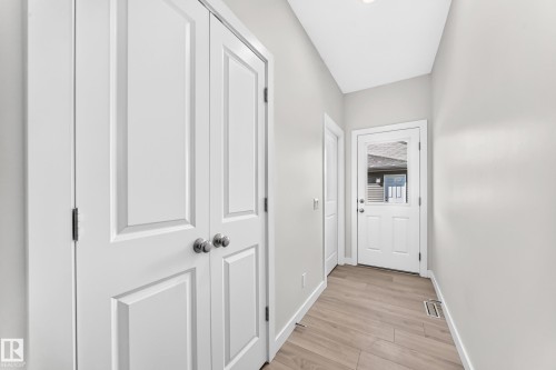 Light wood-finish flooring, recessed ceiling lighting, a white painted door with glass panel, and white trim - 3816 Chrustawka Place Sw, Edmonton, AB - Indoor Photo Showing Other Room