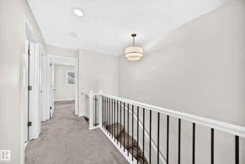 Hallway featuring plush carpet flooring, white trim, recessed lighting, and a modern tiered pendant light fixture - 3816 Chrustawka Place Sw, Edmonton, AB - Indoor Photo Showing Other Room
