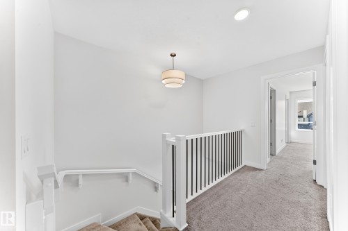 Recessed ceiling light, contemporary chandelier, white painted walls, white trim, and light gray carpet - 3816 Chrustawka Place Sw, Edmonton, AB - Indoor Photo Showing Other Room