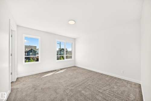 Neutral-toned carpet flooring, white walls, two white-framed windows, and a ceiling-mounted light fixture - 3816 Chrustawka Place Sw, Edmonton, AB - Indoor Photo Showing Other Room