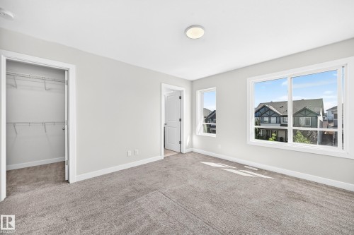 Neutral gray carpeting and walls, multiple windows, a flush-mount ceiling light, and an open closet with wire shelving - 3816 Chrustawka Place Sw, Edmonton, AB - Indoor Photo Showing Other Room