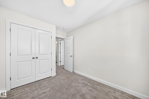 Neutral wall paint, plush carpet flooring, white trim, and a flush mount light fixture - 3816 Chrustawka Place Sw, Edmonton, AB - Indoor Photo Showing Other Room