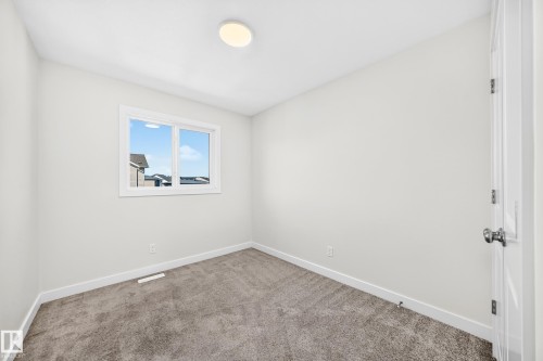 Recessed window, textured carpeting, white trim, flush mount ceiling light, and white door with silver hardware - 3816 Chrustawka Place Sw, Edmonton, AB - Indoor Photo Showing Other Room