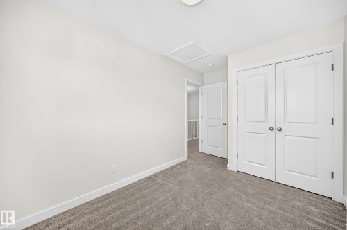 Neutral tone wall finish, plush carpet flooring, white bi-fold closet doors, white interior door, and a flush mount ceiling light - 3816 Chrustawka Place Sw, Edmonton, AB - Indoor Photo Showing Other Room