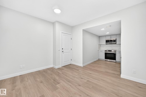 Wood-finish flooring, recessed lighting, white interior door, light gray cabinetry, stainless steel appliances - 3816 Chrustawka Place Sw, Edmonton, AB - Indoor Photo Showing Other Room With Fireplace