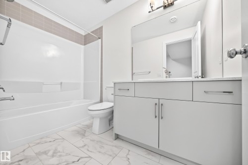 Modern bathroom featuring a single vanity with light cabinetry, a white countertop, and a built-in tub with a shower - 3816 Chrustawka Place Sw, Edmonton, AB - Indoor Photo Showing Bathroom
