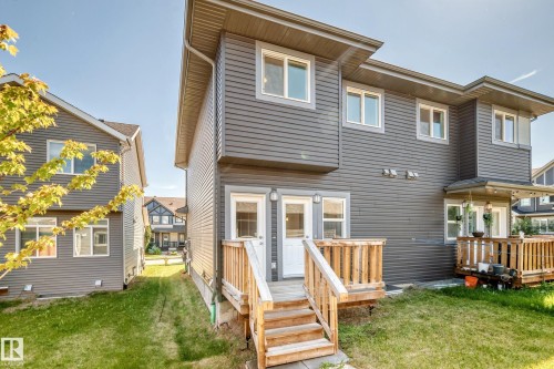 Rear exterior featuring a wooden deck with railing, dual exterior doors, and gray horizontal siding - 3816 Chrustawka Place Sw, Edmonton, AB - Outdoor With Deck Patio Veranda