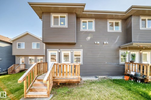 Two-story exterior with horizontal siding, multiple windows, and a wooden deck with stairs to a grass area - 3816 Chrustawka Place Sw, Edmonton, AB - Outdoor With Deck Patio Veranda