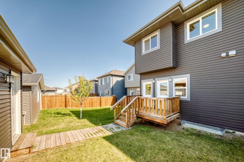 Expansive backyard featuring a wood privacy fence, a wooden deck with railing, and a detached garage - 3816 Chrustawka Place Sw, Edmonton, AB - Outdoor With Exterior