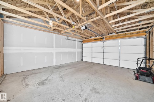 Concrete flooring, exposed wood ceiling trusses, white panel garage door, garage door opener mechanism - 3816 Chrustawka Place Sw, Edmonton, AB - Indoor Photo Showing Garage