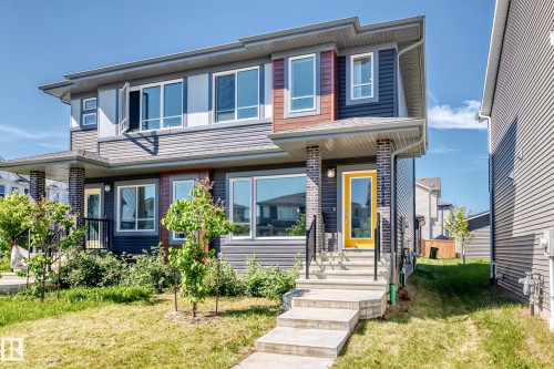 Contemporary exterior with varied siding, brick columns, and a bright yellow front door - 3816 Chrustawka Place Sw, Edmonton, AB - Outdoor With Facade