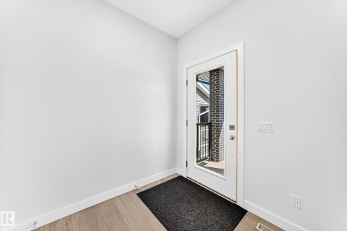 Full-lite entry door, light wood-finish flooring, and white trim - 3816 Chrustawka Place Sw, Edmonton, AB - Indoor Photo Showing Other Room