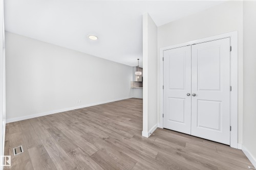 Wood-finish flooring, recessed ceiling lighting, and white bi-fold doors - 3816 Chrustawka Place Sw, Edmonton, AB - Indoor Photo Showing Other Room