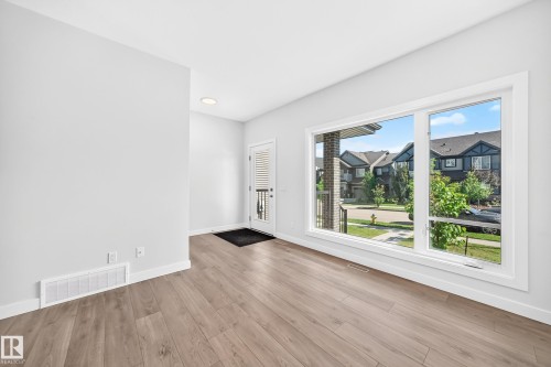 Bright interior featuring wood-finish flooring, white walls, large windows, and recessed lighting - 3816 Chrustawka Place Sw, Edmonton, AB - Indoor Photo Showing Other Room
